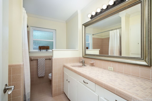 bathroom with toilet, vanity, tile walls, and ornamental molding