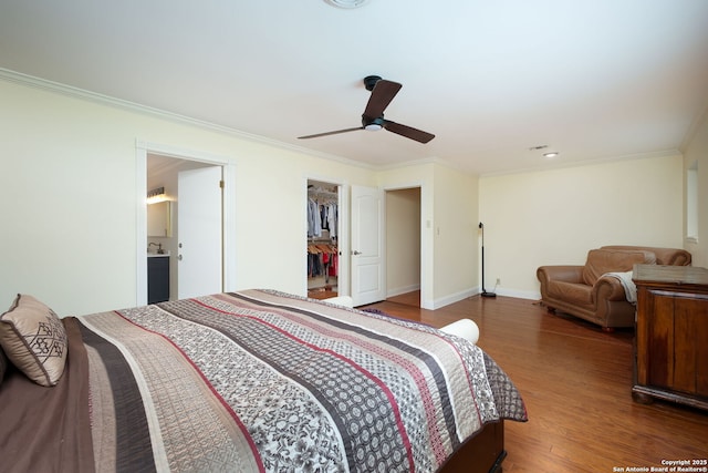 bedroom with hardwood / wood-style floors, a closet, a walk in closet, ceiling fan, and crown molding