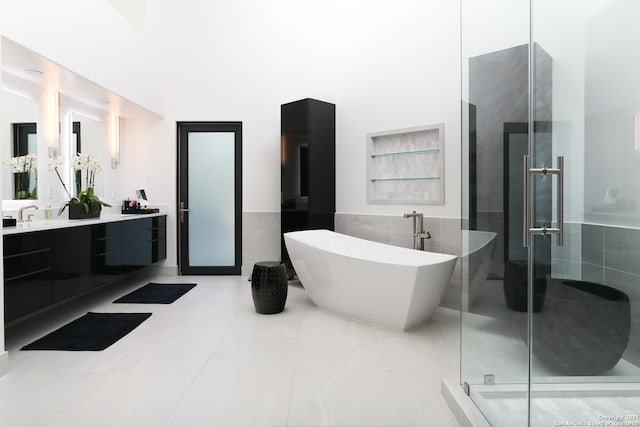 bathroom featuring tile walls, vanity, tile patterned flooring, and plus walk in shower