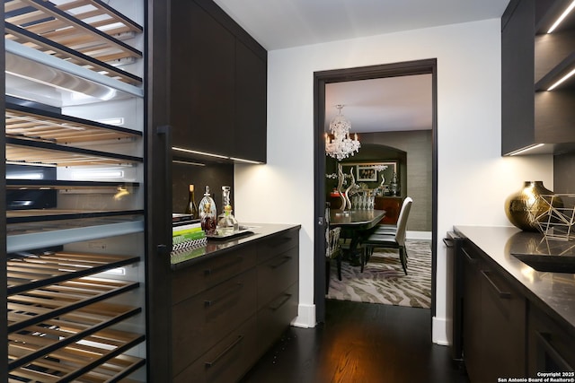 bar featuring dark hardwood / wood-style floors and a chandelier