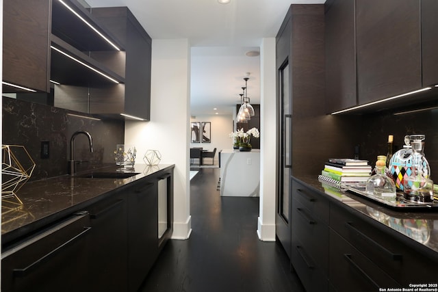 kitchen with pendant lighting, backsplash, sink, and dark stone countertops