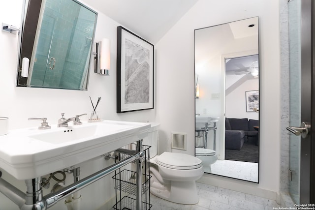 bathroom with a shower with door, lofted ceiling, and toilet