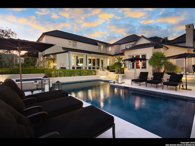 pool at dusk featuring a patio