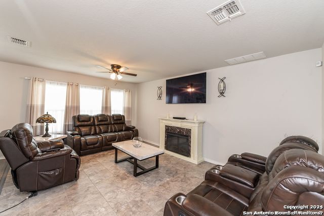 living room featuring a premium fireplace and ceiling fan