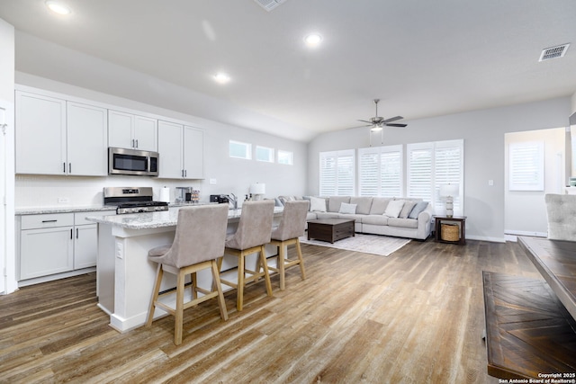 kitchen featuring stainless steel appliances, an island with sink, a breakfast bar area, and white cabinets