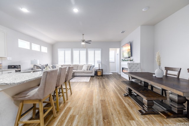 dining room with ceiling fan, sink, and light hardwood / wood-style flooring