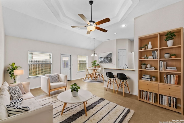 living room with ceiling fan, a raised ceiling, and vaulted ceiling