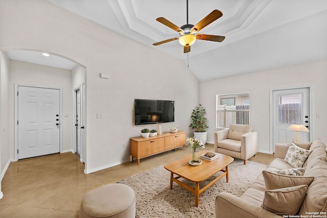 living room with ceiling fan, lofted ceiling, and a tray ceiling