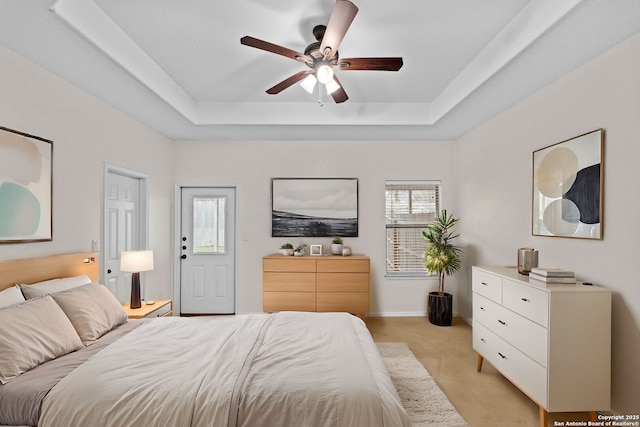 bedroom with light carpet, a raised ceiling, and ceiling fan