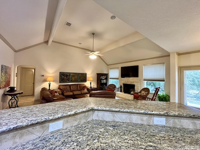 kitchen featuring vaulted ceiling with beams, ornamental molding, light stone countertops, and ceiling fan