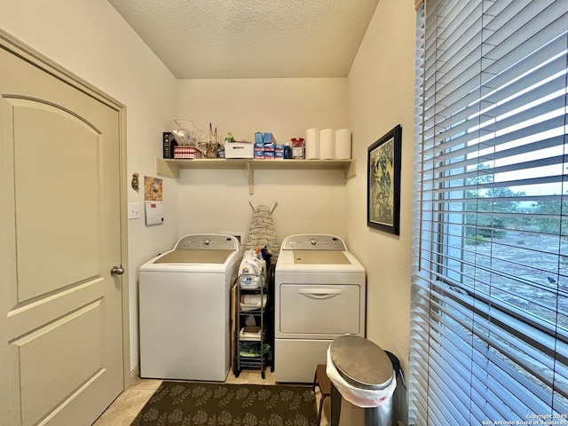 laundry room with light tile patterned flooring, washing machine and clothes dryer, and a textured ceiling