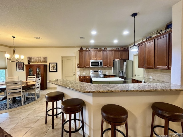 kitchen featuring a kitchen breakfast bar, decorative backsplash, hanging light fixtures, kitchen peninsula, and stainless steel appliances