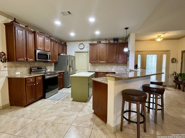 kitchen featuring stainless steel appliances, a center island, a kitchen breakfast bar, decorative light fixtures, and kitchen peninsula