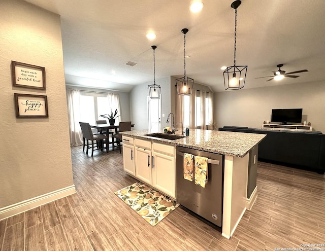 kitchen with sink, light stone counters, an island with sink, white cabinets, and stainless steel dishwasher