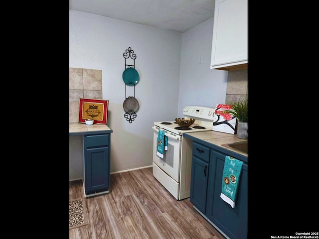 kitchen featuring blue cabinets, tasteful backsplash, white electric range oven, and light hardwood / wood-style flooring