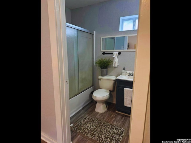 full bathroom featuring hardwood / wood-style flooring, combined bath / shower with glass door, sink, and toilet