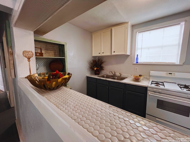 kitchen featuring white cabinetry, sink, and white gas range oven