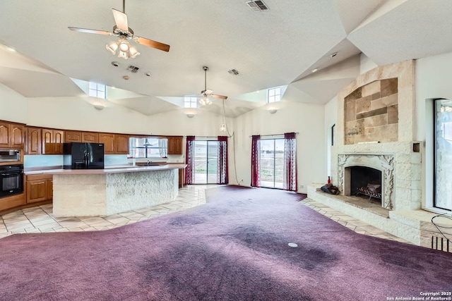 unfurnished living room with ceiling fan, light colored carpet, a large fireplace, and high vaulted ceiling