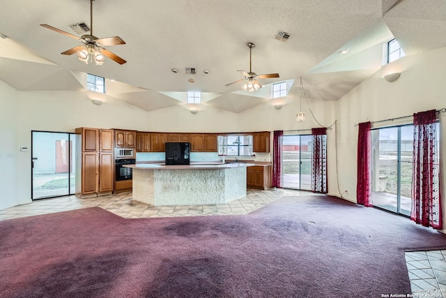 kitchen featuring ceiling fan, light colored carpet, a center island, and black appliances