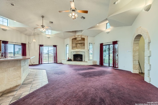 unfurnished living room with a large fireplace, plenty of natural light, high vaulted ceiling, and light carpet