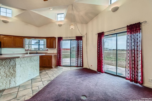 kitchen featuring hanging light fixtures, light colored carpet, and high vaulted ceiling