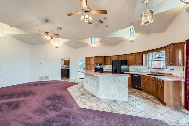 kitchen featuring decorative light fixtures, a kitchen island, light colored carpet, ceiling fan with notable chandelier, and black appliances