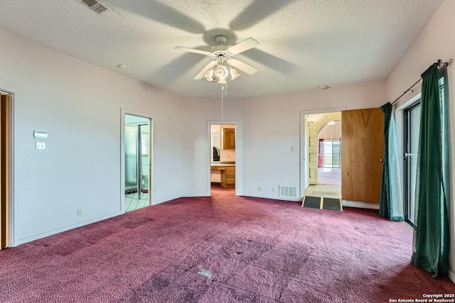 unfurnished bedroom with ceiling fan, connected bathroom, carpet, and a textured ceiling