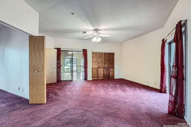 unfurnished living room featuring dark colored carpet, a textured ceiling, and ceiling fan