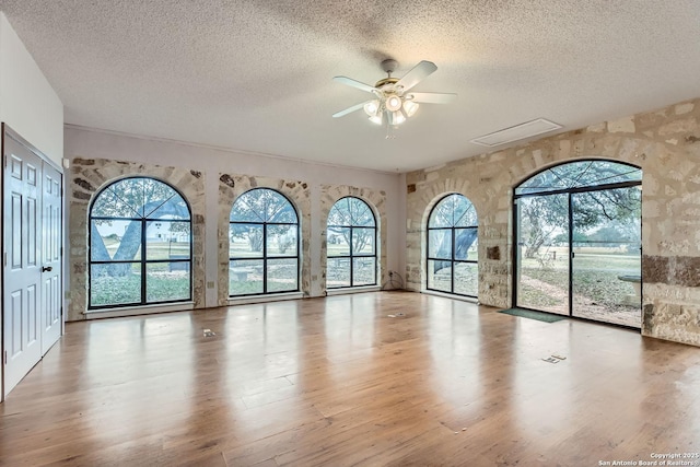 empty room featuring a wealth of natural light, light hardwood / wood-style flooring, and a textured ceiling