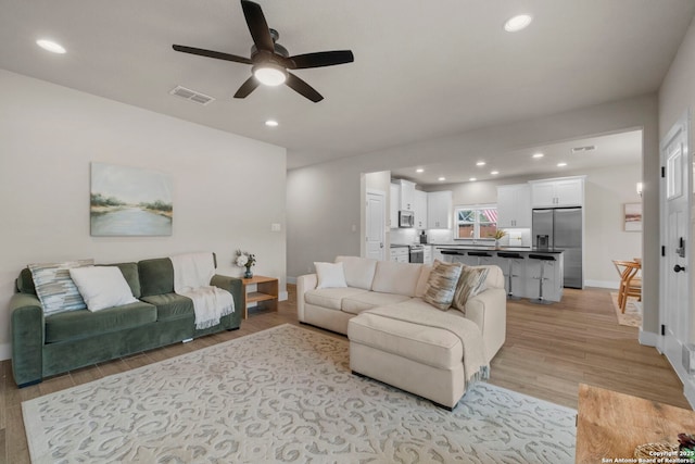 living room featuring light hardwood / wood-style floors and ceiling fan