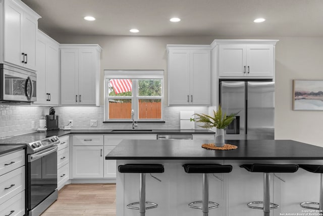 kitchen with sink, a breakfast bar, white cabinets, and appliances with stainless steel finishes