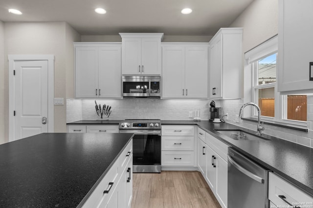 kitchen with appliances with stainless steel finishes, sink, decorative backsplash, and white cabinets