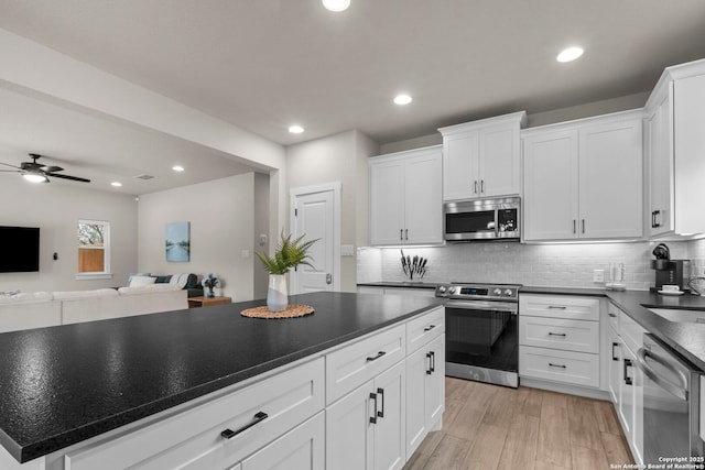 kitchen with white cabinetry, backsplash, ceiling fan, light hardwood / wood-style floors, and stainless steel appliances