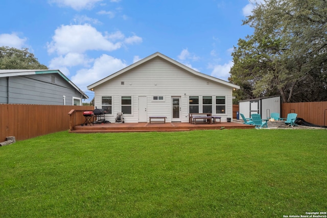 back of property with a wooden deck, an outdoor fire pit, a yard, and a shed