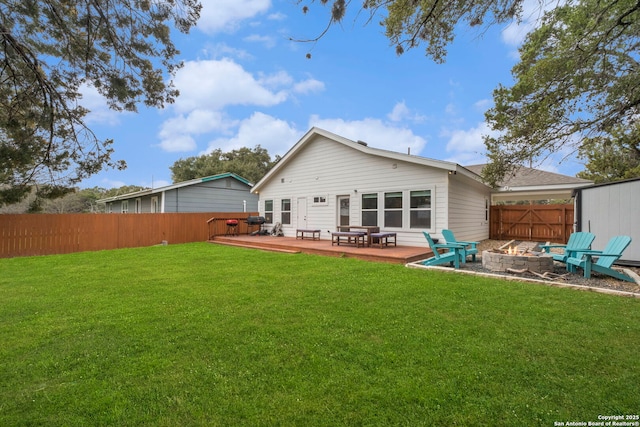 rear view of house with a wooden deck, a lawn, and an outdoor fire pit