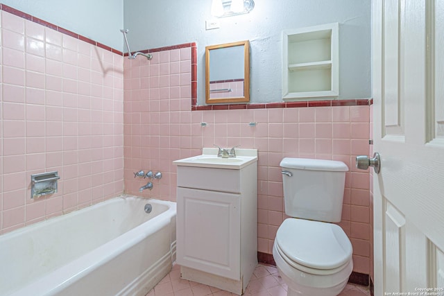 full bathroom featuring toilet, tile walls, vanity, tiled shower / bath combo, and tile patterned flooring