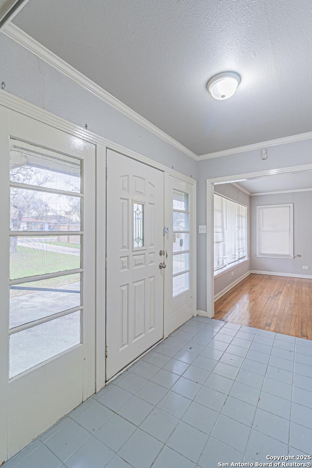 foyer entrance featuring light tile patterned floors, crown molding, and a textured ceiling