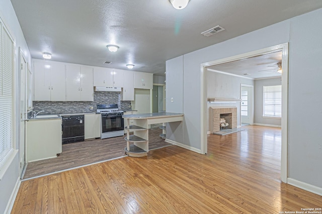 kitchen with dishwasher, tasteful backsplash, white cabinets, white gas range, and light wood-type flooring