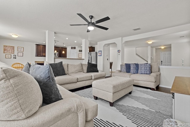 living room with ceiling fan, wood-type flooring, and a textured ceiling