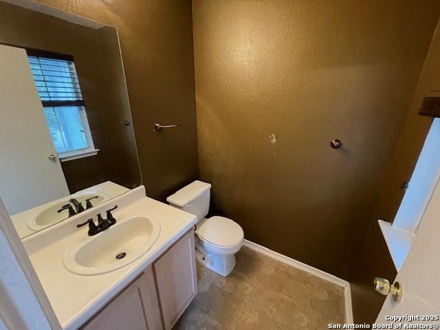 bathroom with toilet, vanity, and baseboards