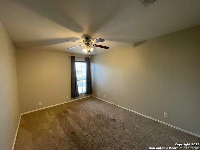 unfurnished room with ceiling fan, dark colored carpet, visible vents, and baseboards