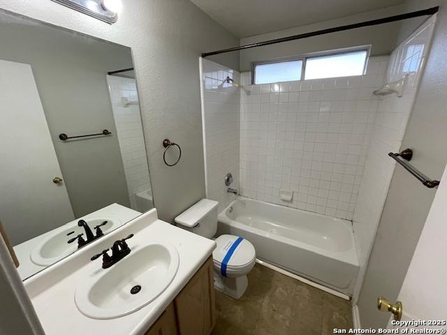 full bath with toilet, shower / bath combination, a textured wall, and vanity