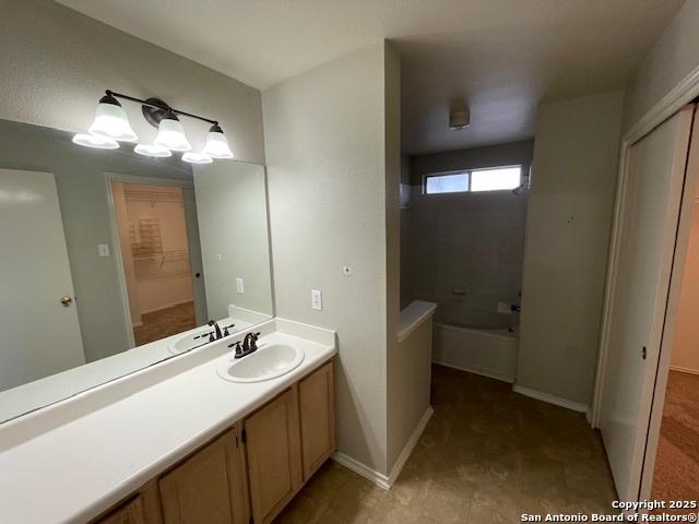 bathroom featuring  shower combination, vanity, and baseboards