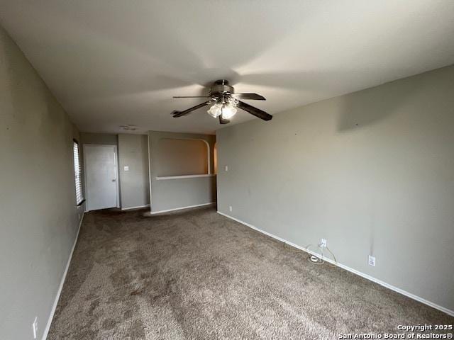 carpeted spare room featuring baseboards and a ceiling fan