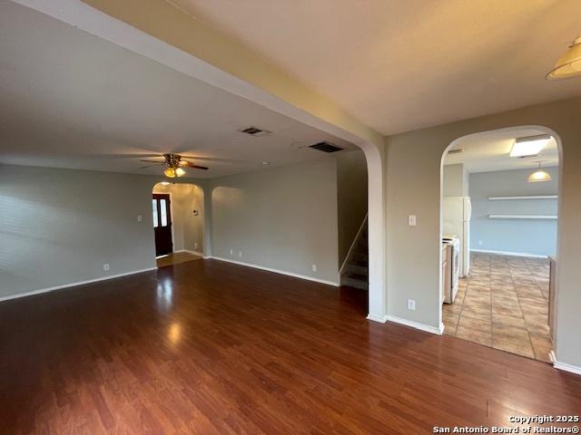 empty room with visible vents, stairs, arched walkways, and wood finished floors