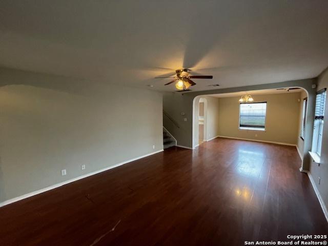 spare room with stairs, dark wood-style flooring, arched walkways, and baseboards