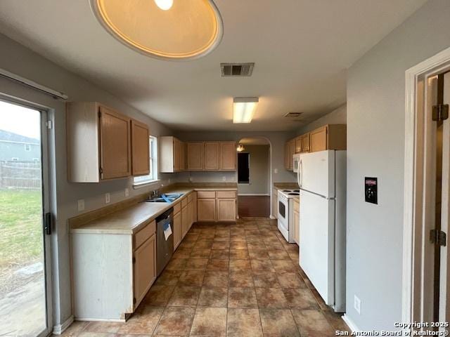 kitchen featuring white appliances, a sink, visible vents, light countertops, and light brown cabinetry