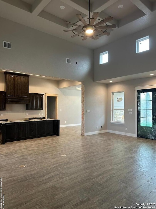 unfurnished living room featuring coffered ceiling, a wealth of natural light, light hardwood / wood-style floors, and ceiling fan