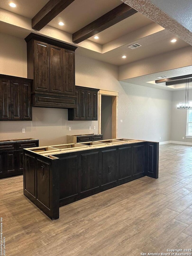 kitchen with light hardwood / wood-style flooring, dark brown cabinetry, and beamed ceiling