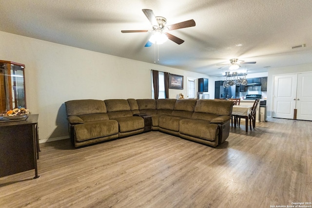 living room featuring ceiling fan, wood-type flooring, and a textured ceiling